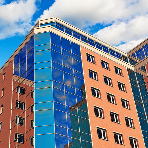 Modern glass reflective city business office buildings over blue sky with clouds